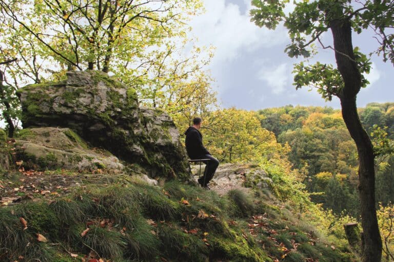 Wanderer sitzt auf Kaiserstuhl im Herbstwald